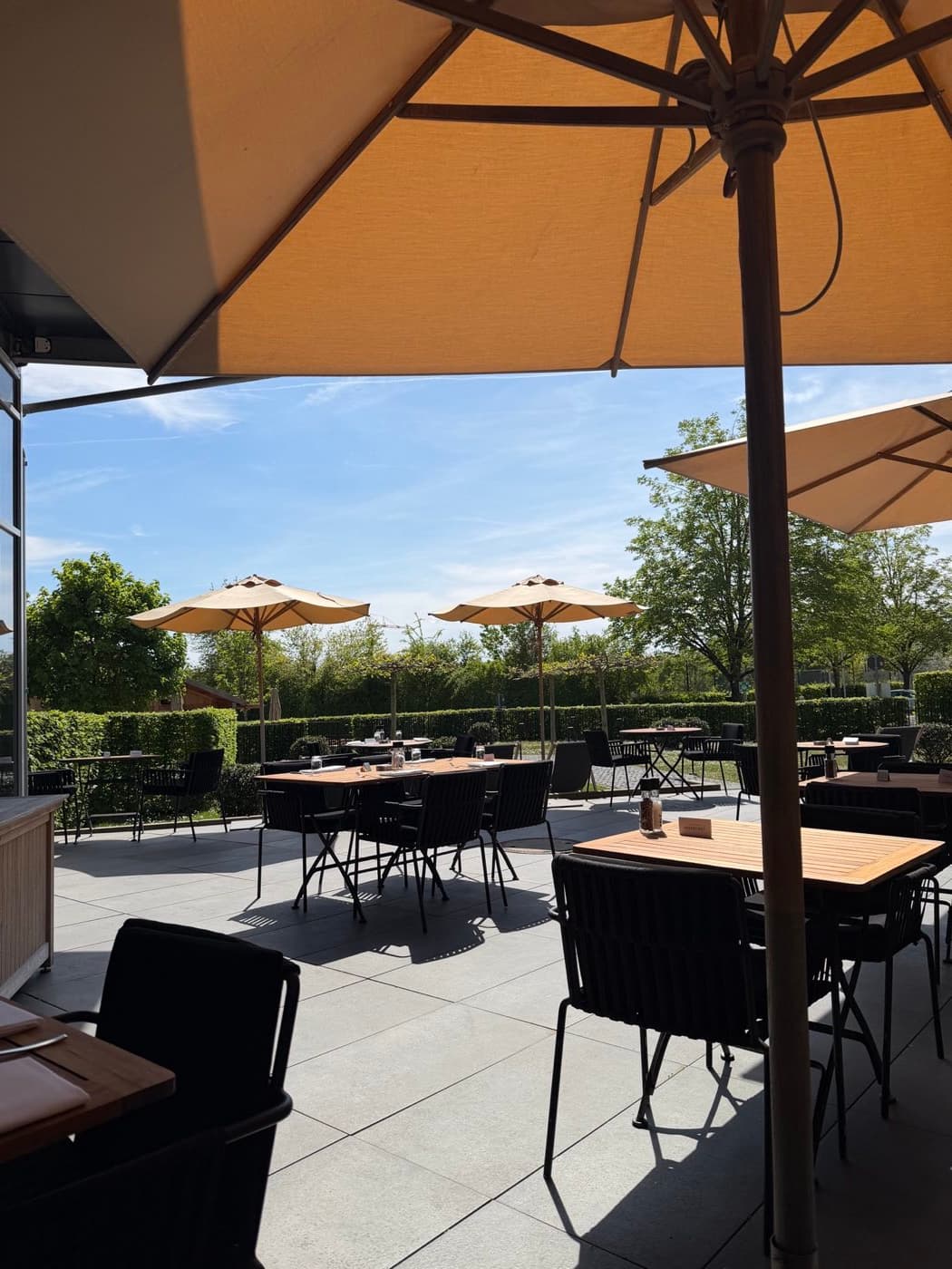Terrassenbereich des Infinity Hotel München mit Bestuhlung, Sonnenschirmen und ruhiger Tagesatmosphäre