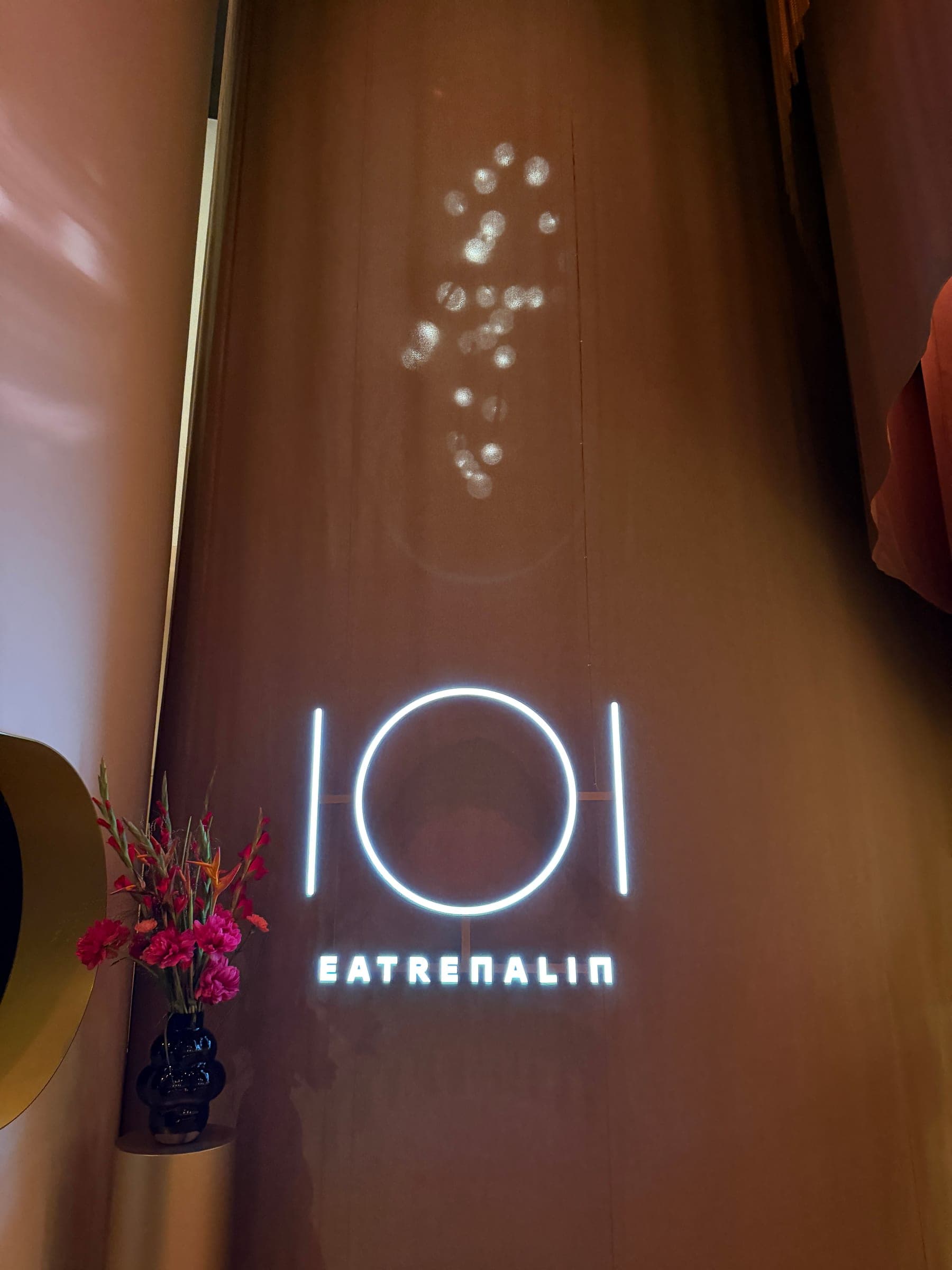 Leuchtendes Eatrenalin-Logo in warmer Atmosphäre mit floraler Dekoration